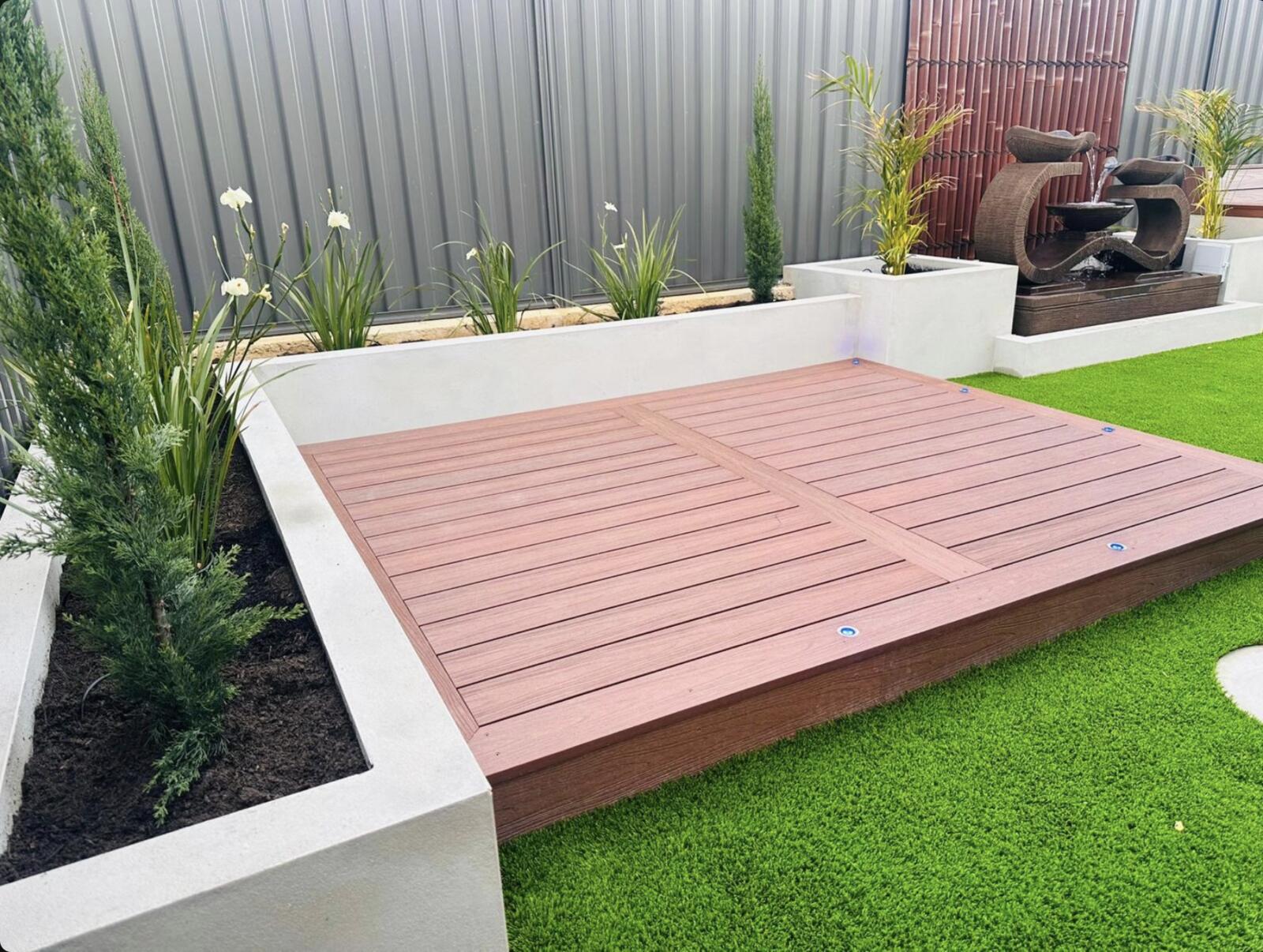 Composite deck bordered by rendered garden beds, turf and a water feature