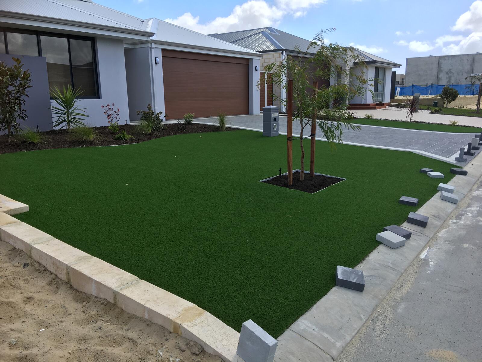 Front yard artificial turf beside a paved driveway