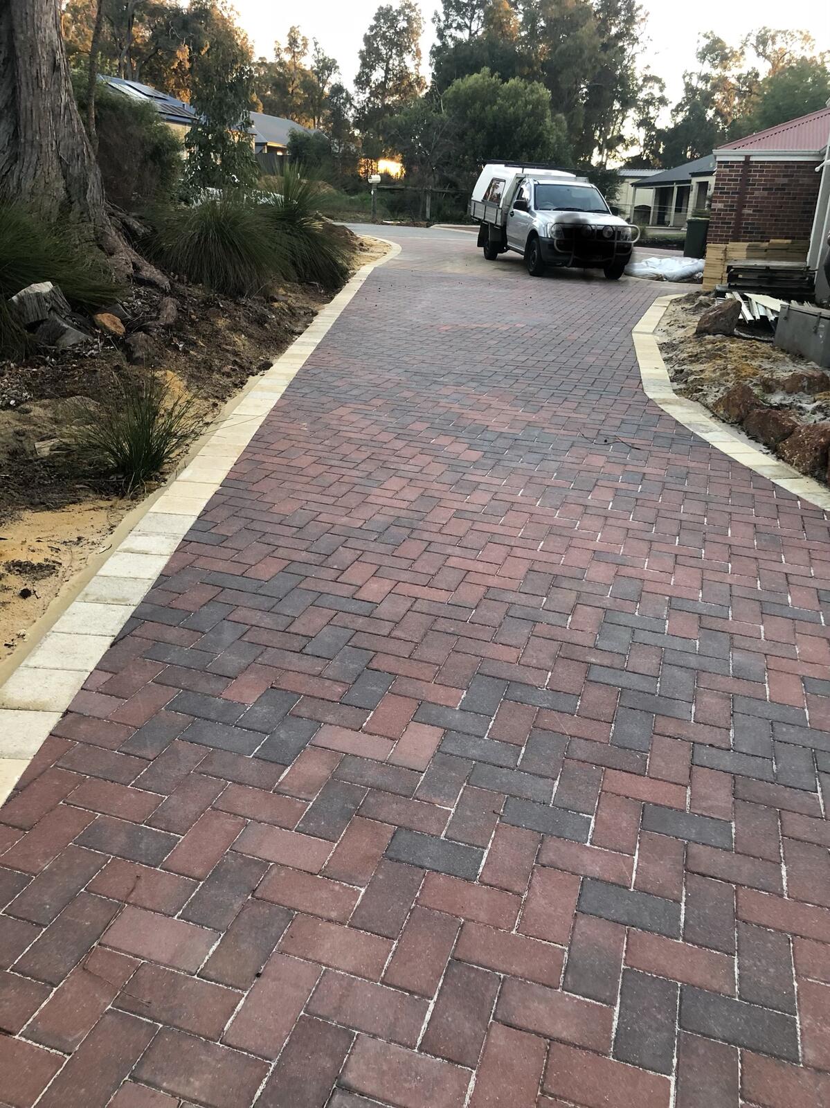 Herringbone brick driveway paving in a treed front yard
