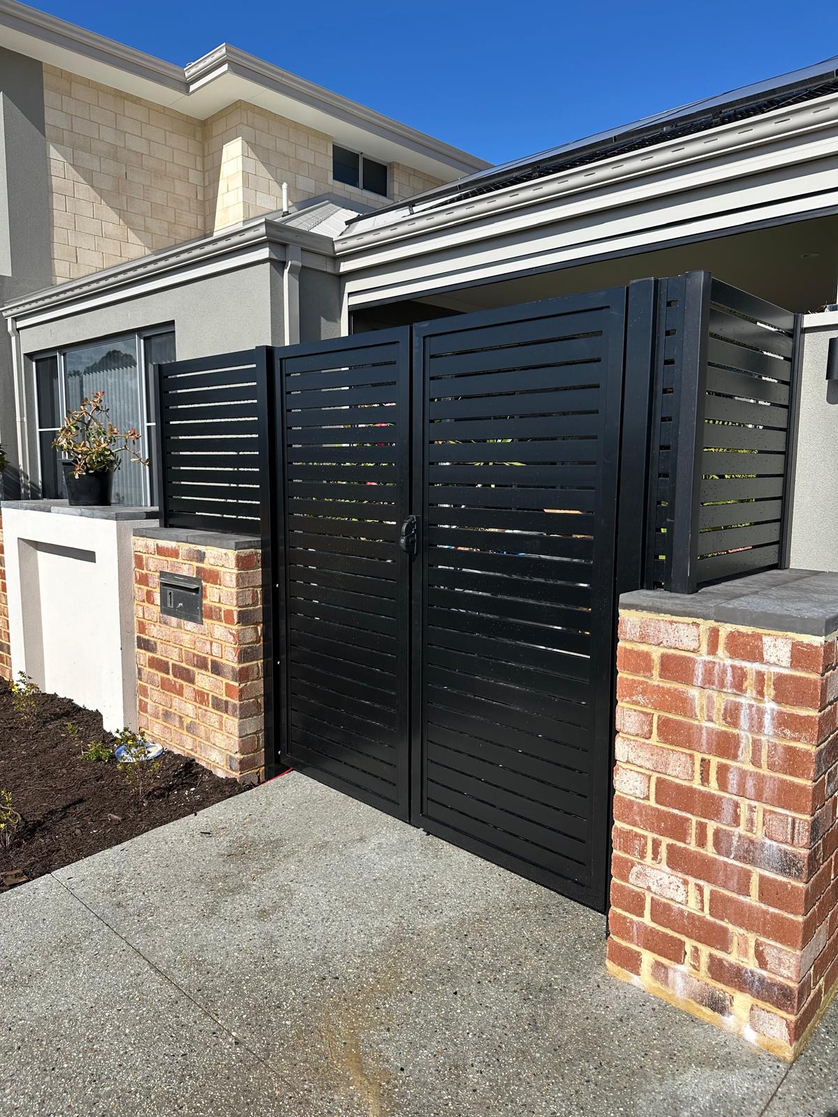 Black slatted feature gate with brick pillars