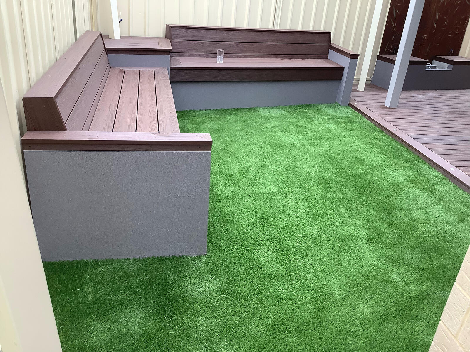 Composite deck bench seating beside artificial turf