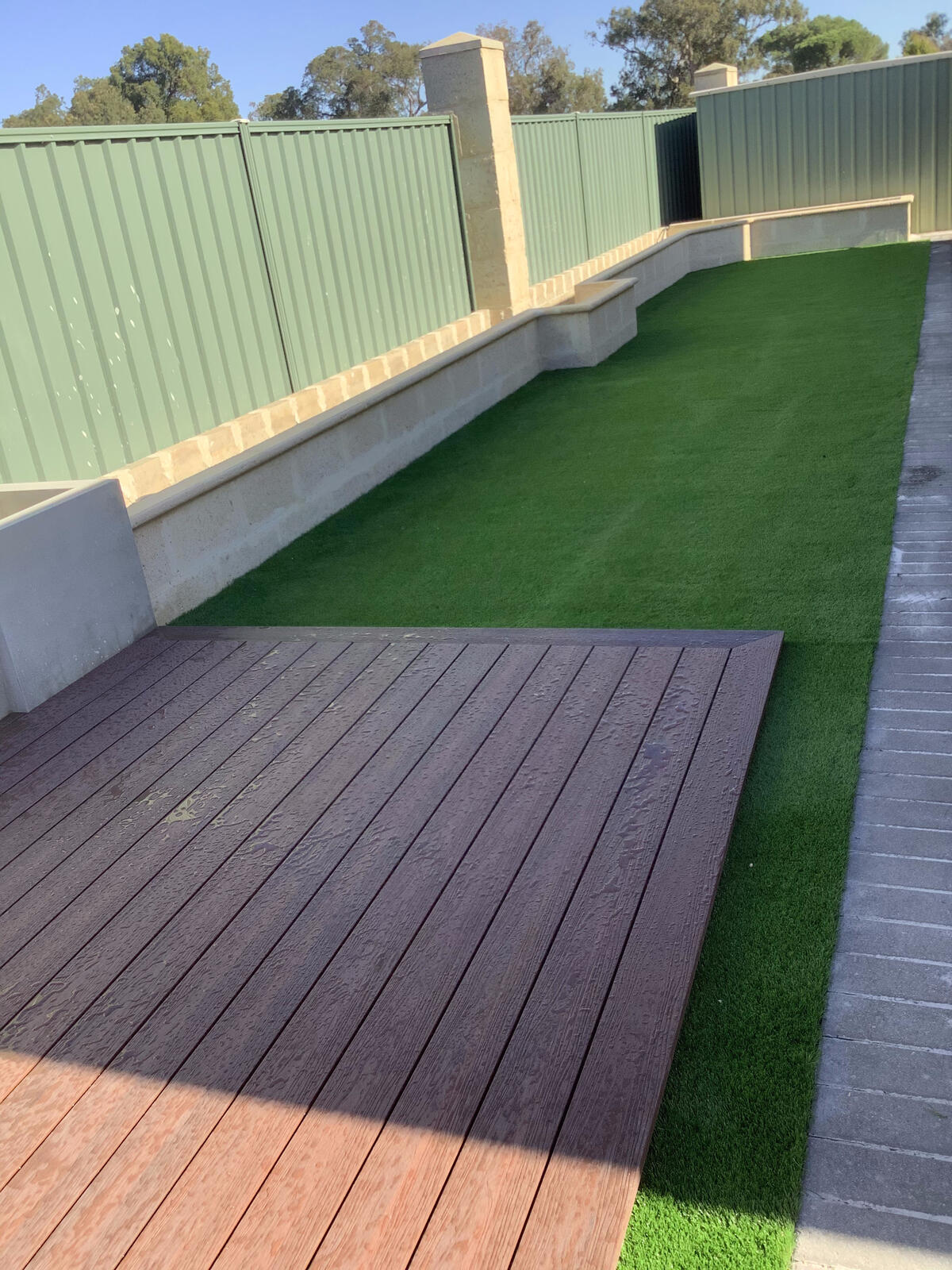Backyard with turf, composite decking and rendered bench seating