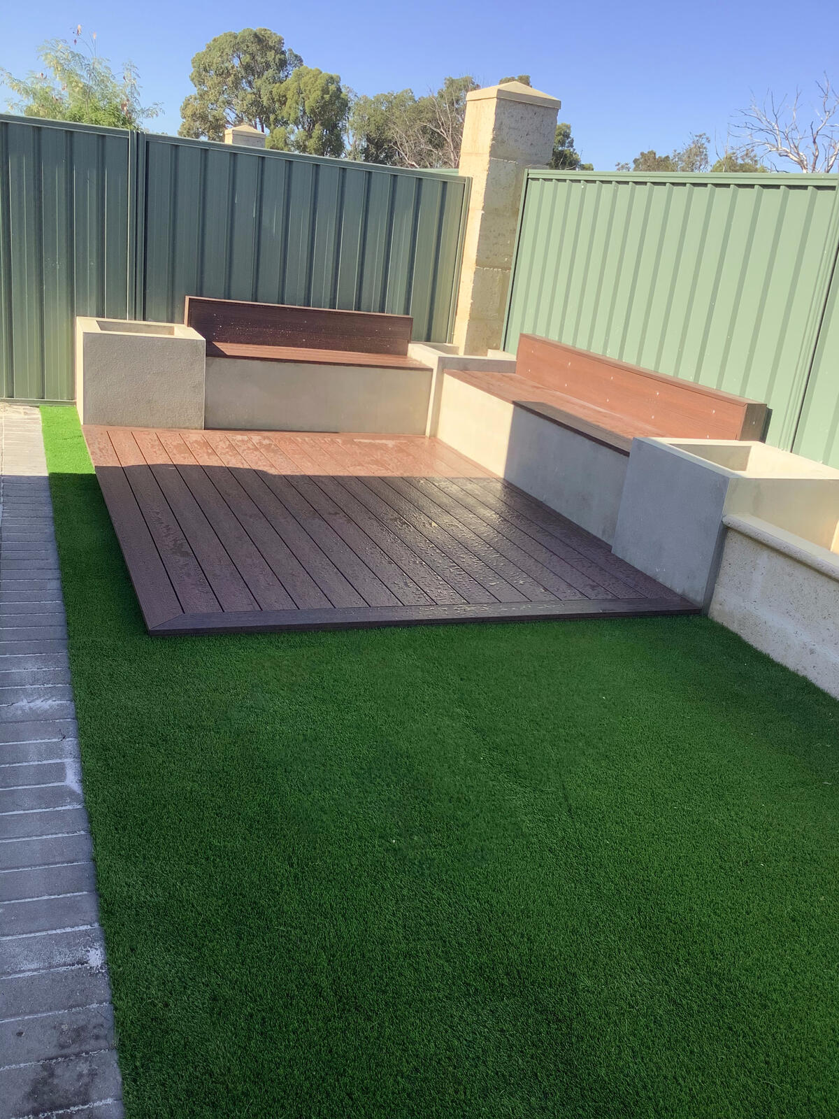 Backyard corner with turf, decking and rendered bench seating