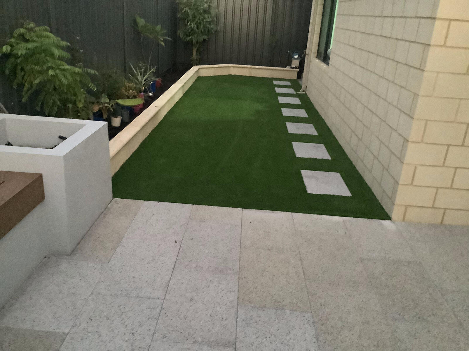 Turf and paving bordered by a rendered limestone garden bed