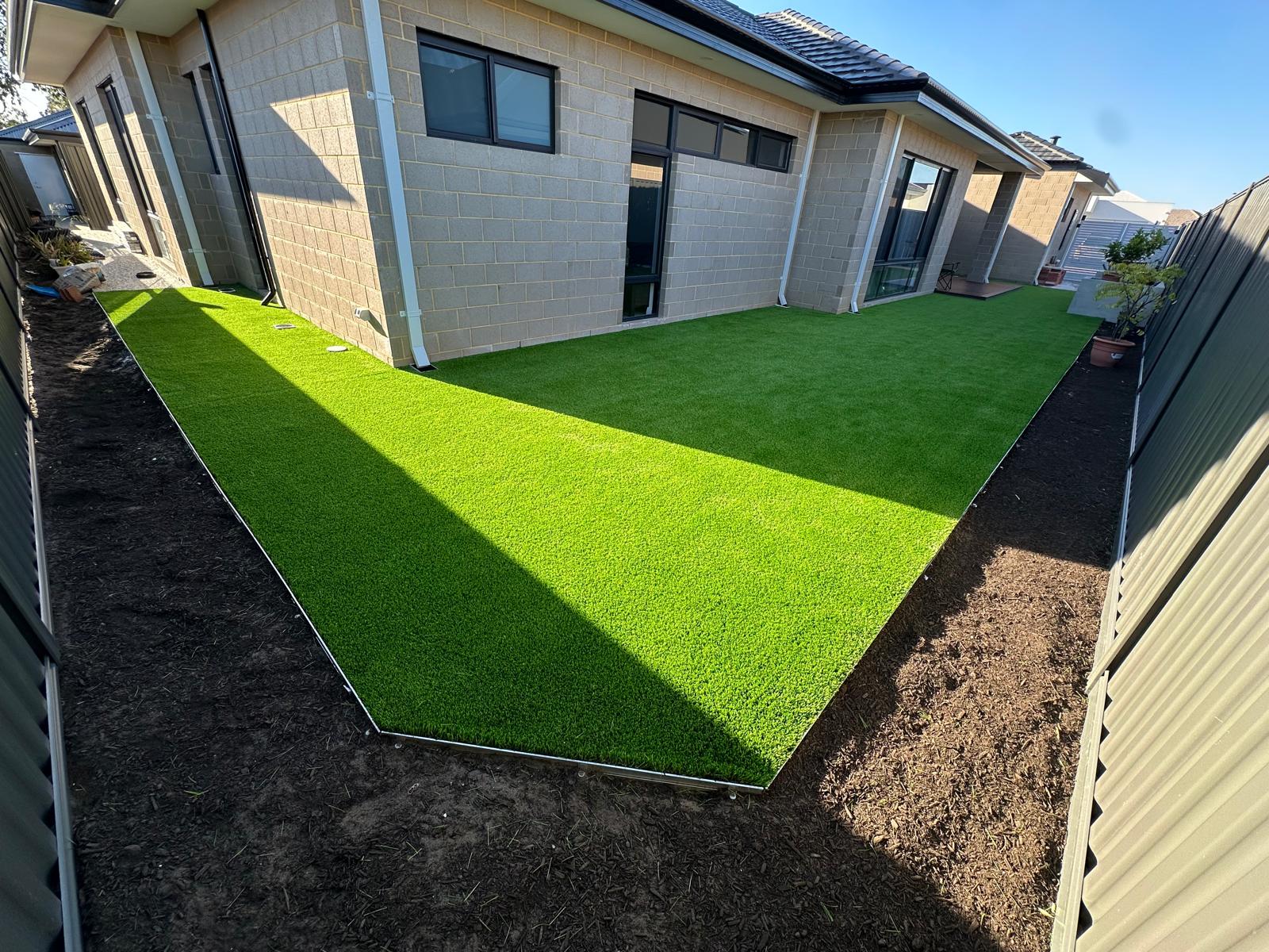 Artificial turf backyard installation at dusk